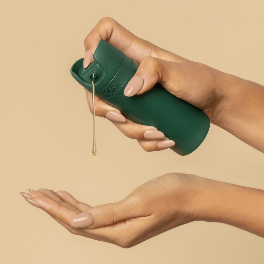 A woman is pumping out shampoo with a beautiful travel container from Ries.